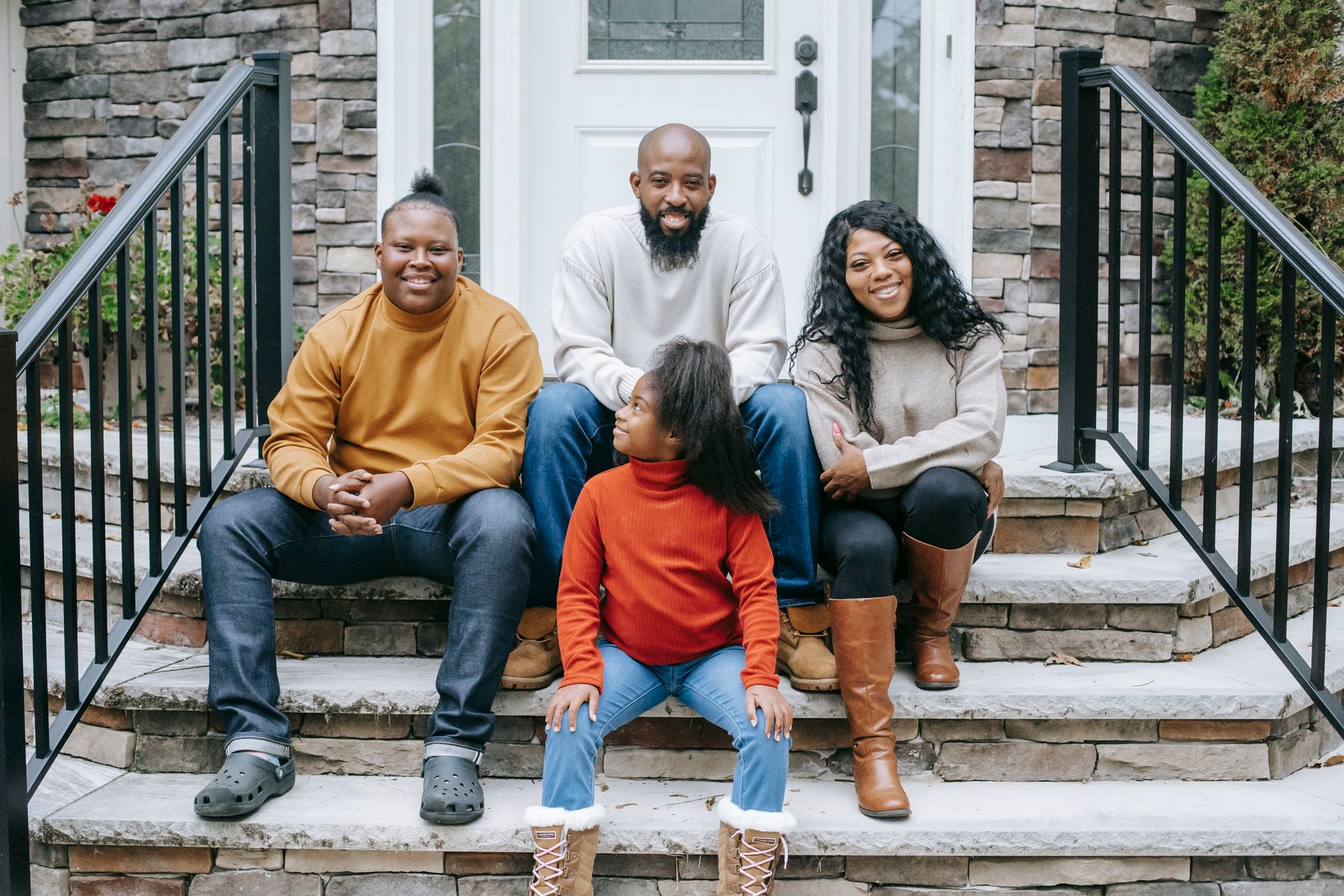 Family smiling together on the steps of their home